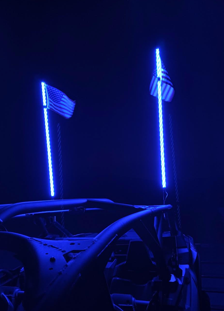 Pair of blue illuminated LED whips with flags at night