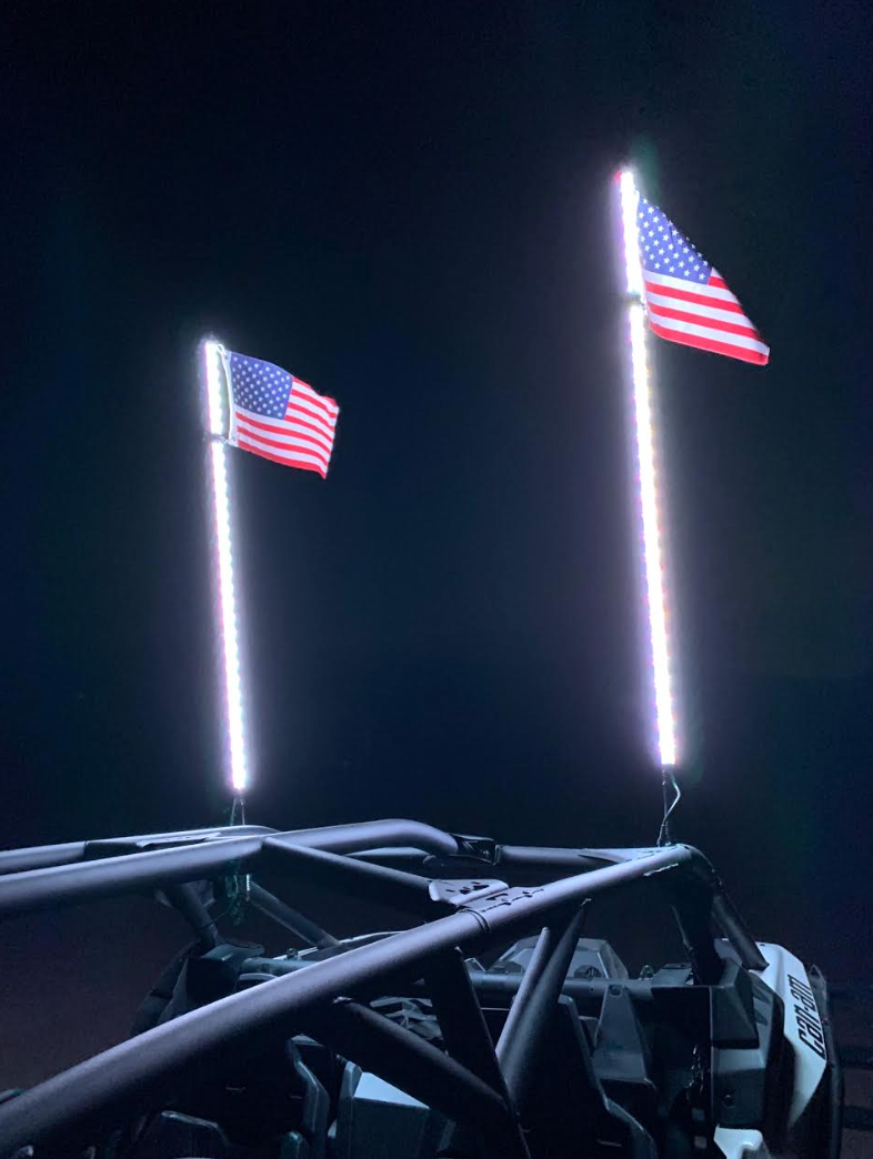 Pair of illuminated LED whips with American flags at night
