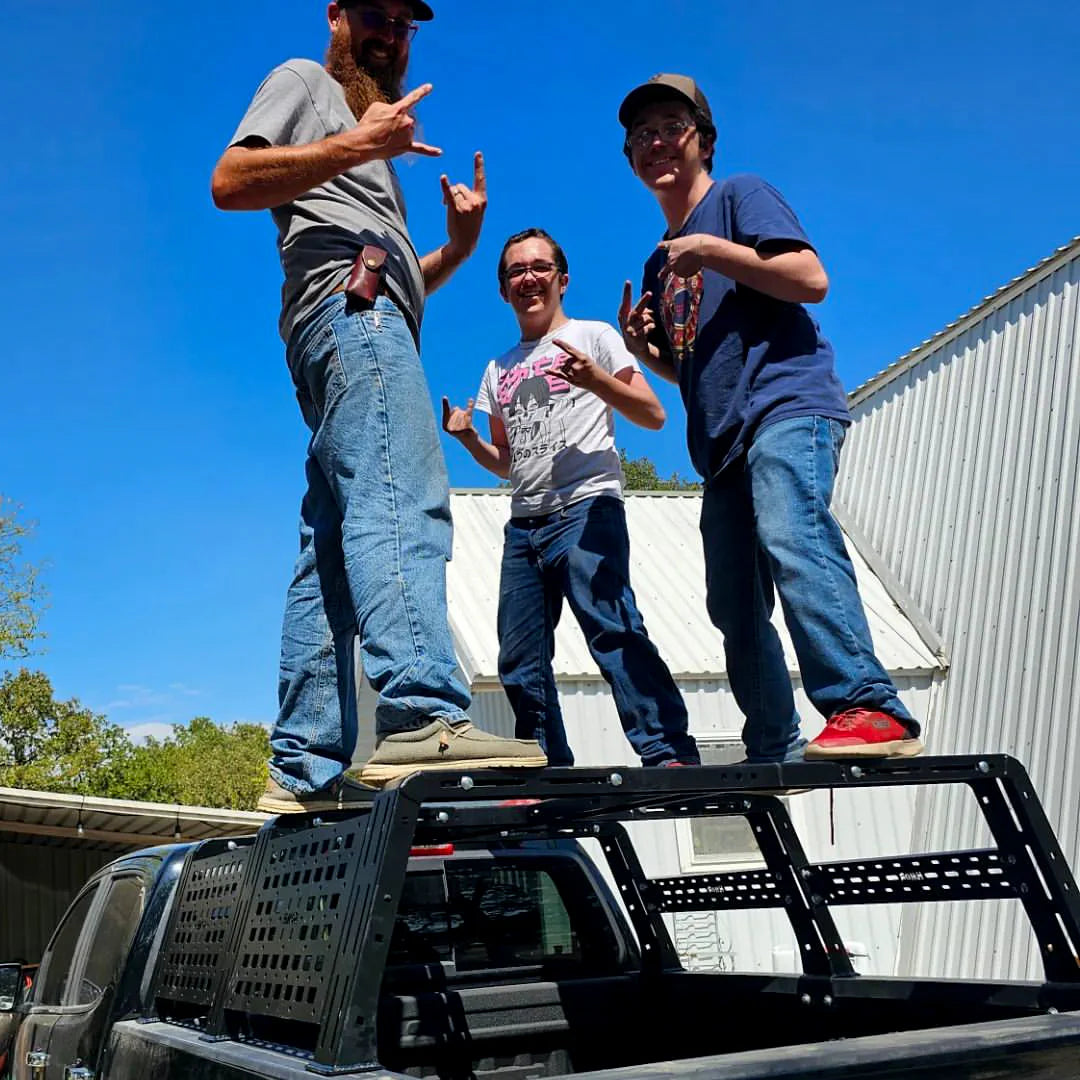 Three people standing on the rack of an overland pickup