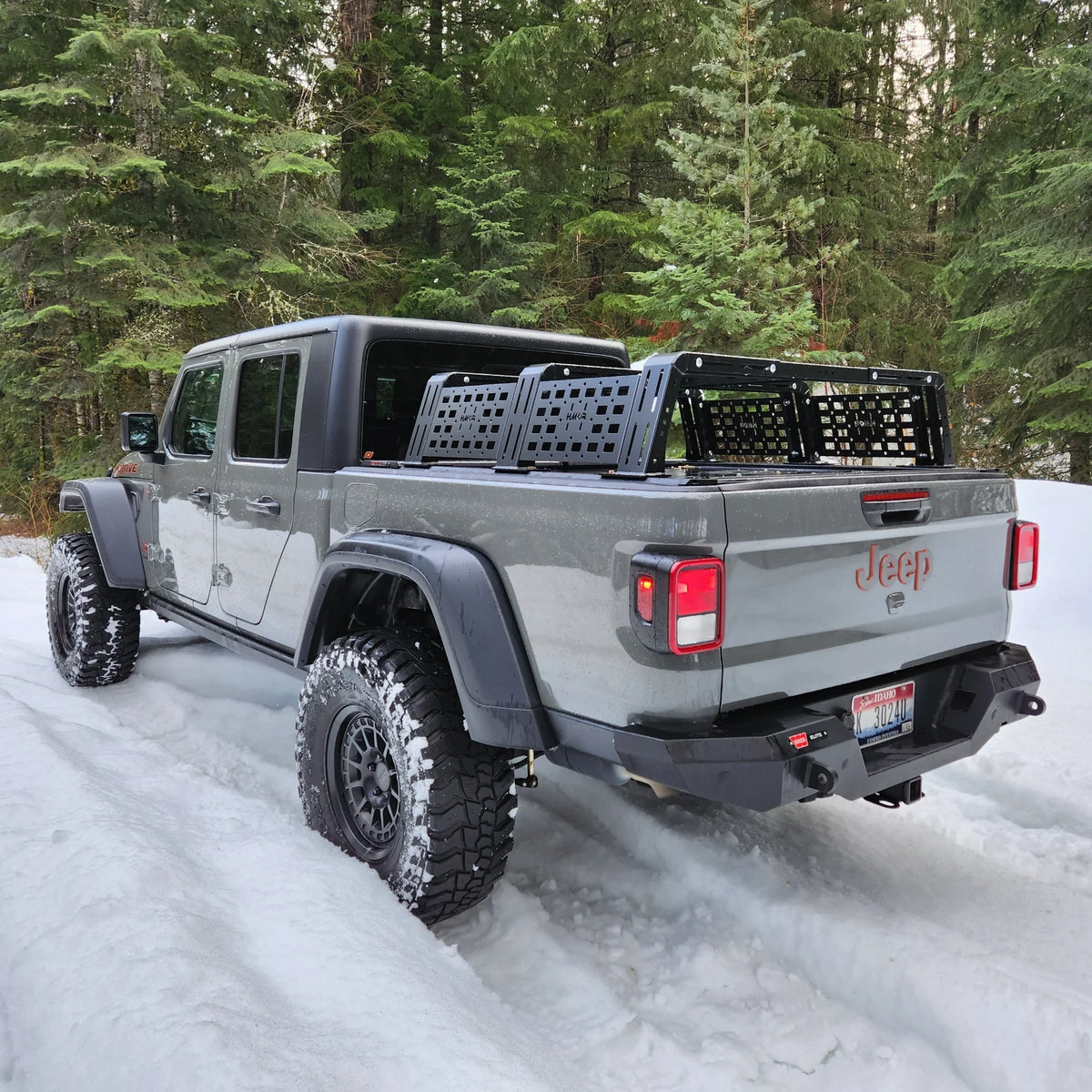 White Jeep Gladiator with an overland bed rack on a snowy road