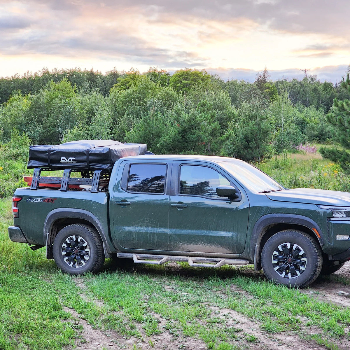 Gray pickup with rack and rooftop tent parked in a grassy field