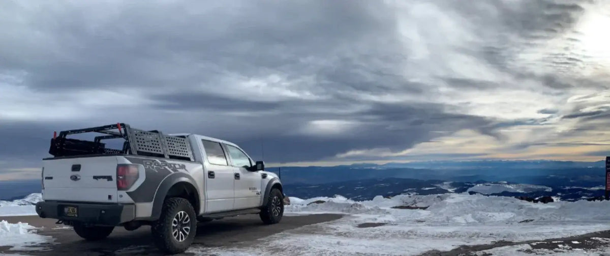 White Toyota Tacoma in a snowy landscape beneath a stormy sky