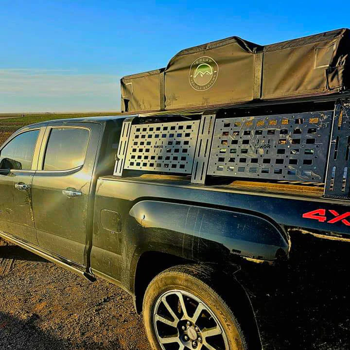 Black pickup with bed rack and rooftop tent in warm evening light