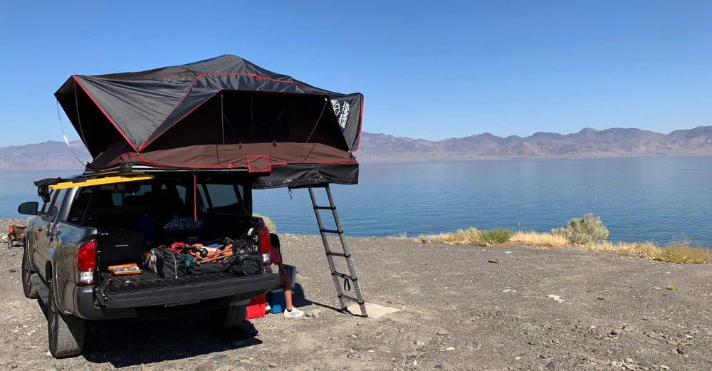 Vehicle with a rooftop tent parked beside a lake
