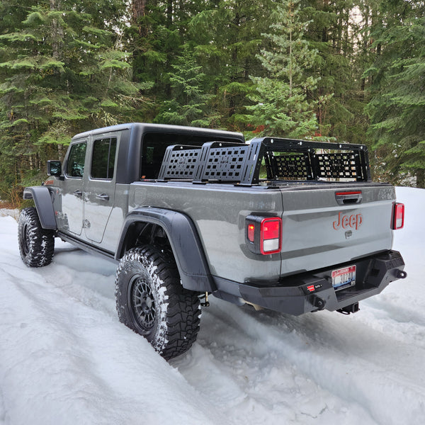 White Jeep Gladiator with a bed rack on a snowy road