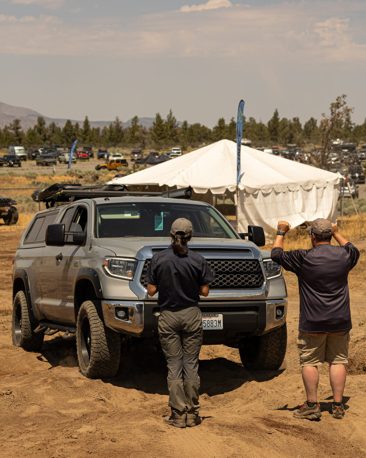 Tan pickup with an overland rack at an outdoor expo