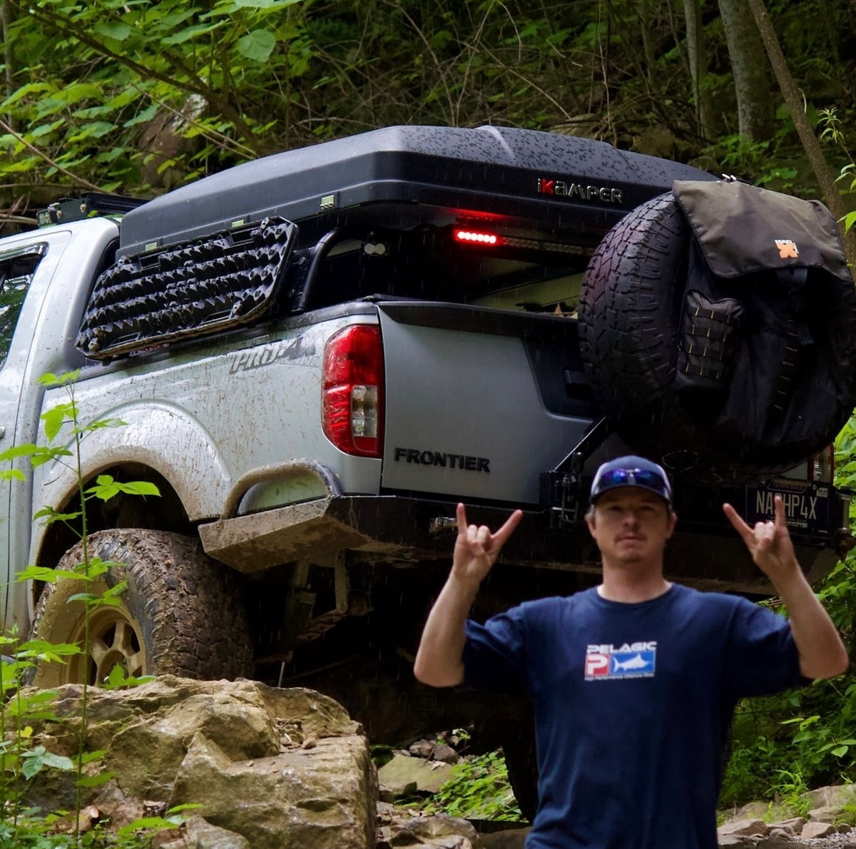 Person inspecting the underside of an off-road truck on a rocky trail