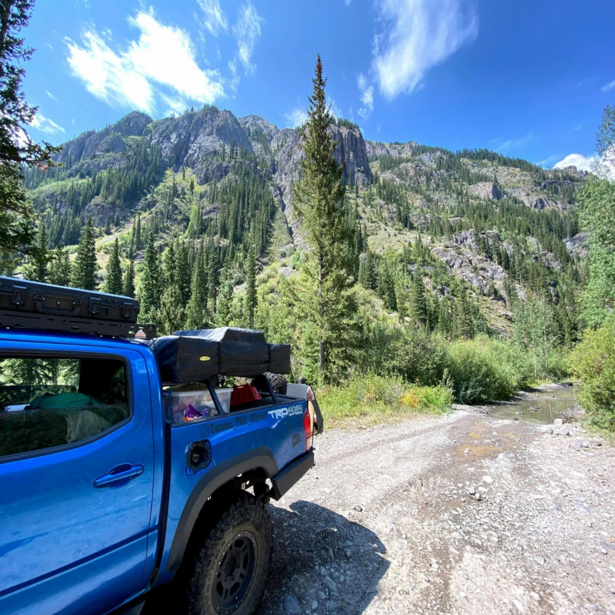Blue pickup with a Heavy Metal Off-Road bed rack in a mountain landscape