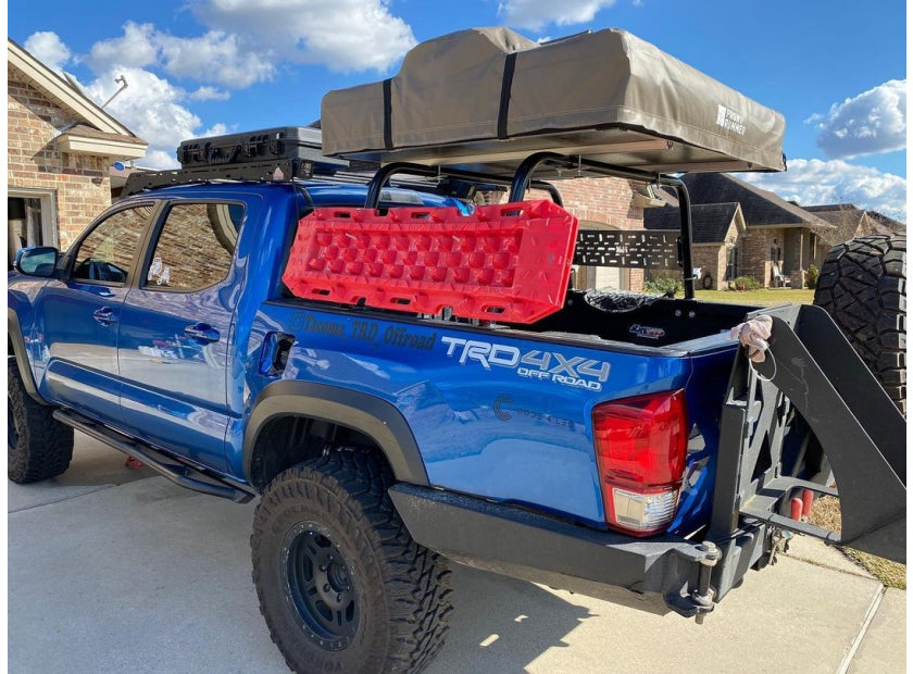 Blue Toyota Tacoma with a rooftop tent, truck bed rack, and mounted red fuel can