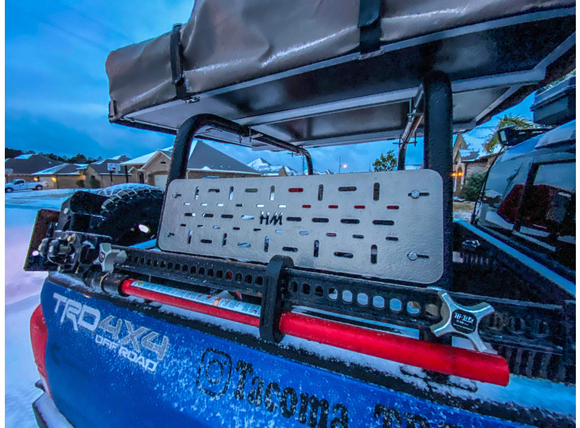 Toyota Tacoma rack carrying a rooftop tent with a Hi-Lift jack mounted to its side